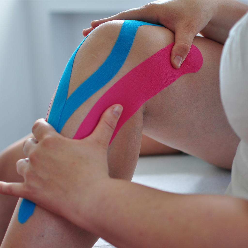 Knie wird mit blauem und rotem Band getaped